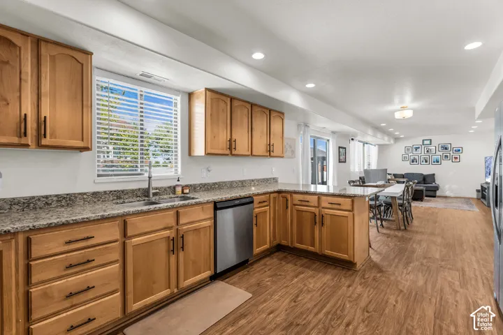 Wood-finish flooring throughout, kitchen featuring wood cabinetry, granite-style countertops, stainless steel appliances, and recessed lighting