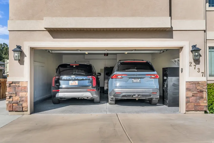 Two-car garage with epoxy flooring, integrated shelving, and stone veneer accents