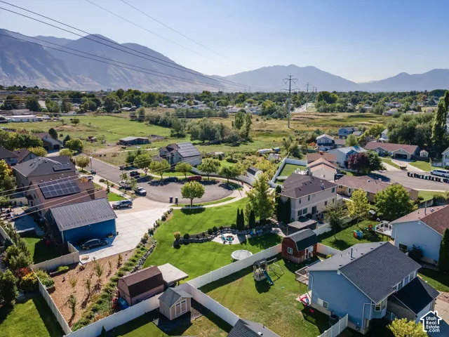 Expansive residential property with a detached blue garage, a large manicured lawn, and multiple storage sheds