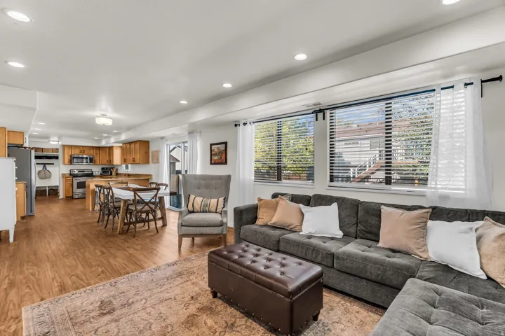 Open-concept living space with wood-finish flooring, recessed lighting, and large windows