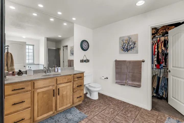 Vanity with extensive storage, stone countertop, tile flooring, built-in recessed lighting, and a walk-in closet