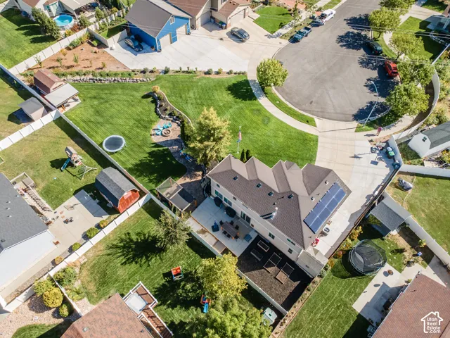 Expansive backyard with a manicured lawn, established landscaping, and a patio area