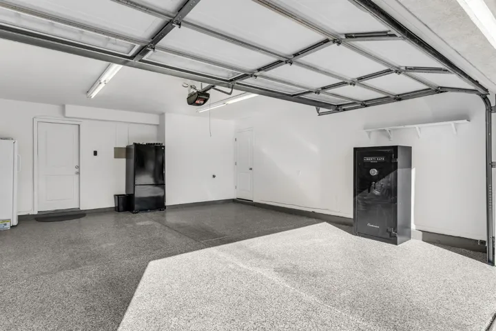 Garage featuring an epoxy-coated floor, overhead lighting, and white walls