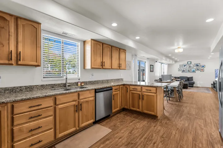 Wood-finish flooring throughout, kitchen featuring wood cabinetry, granite-style countertops, stainless steel appliances, and recessed lighting