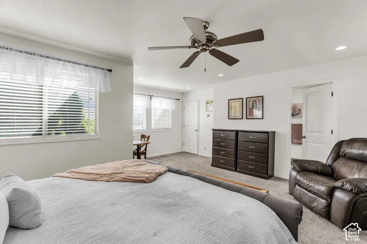 Expansive room featuring multiple windows with horizontal blinds, neutral carpeting, a ceiling fan with integrated lighting, and recessed ceiling lights