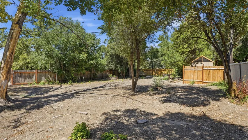 Expansive lot with mature trees, perimeter fencing, and a detached shed