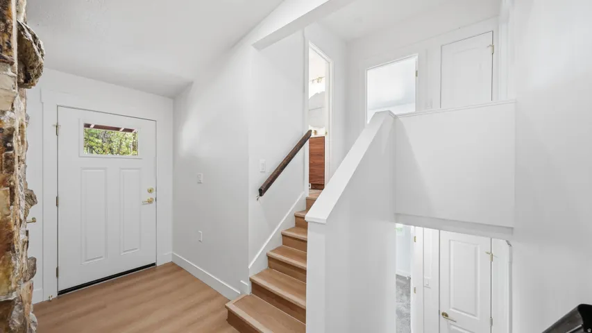 Entryway featuring wood-finish flooring, a white paneled door with transom window, and a stone accent wall