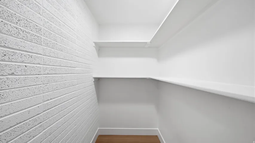 White painted brick-finish accent wall, built-in shelving, wood-finish flooring