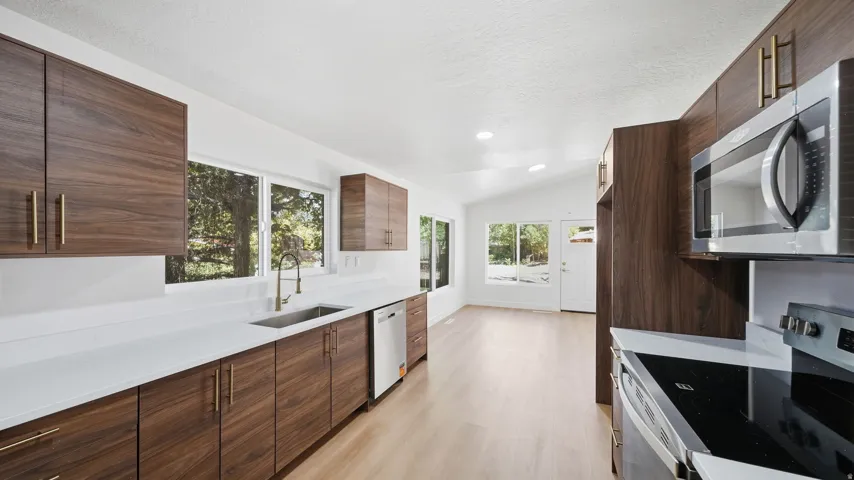 Modern kitchen with wood-finish cabinetry, white countertops, stainless steel appliances, and wood-finish flooring