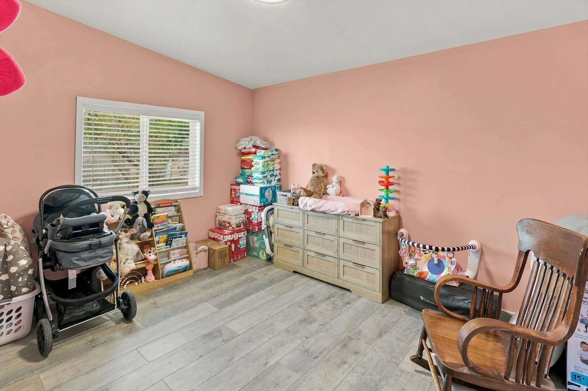 Wood-finish flooring and a single window with horizontal blinds