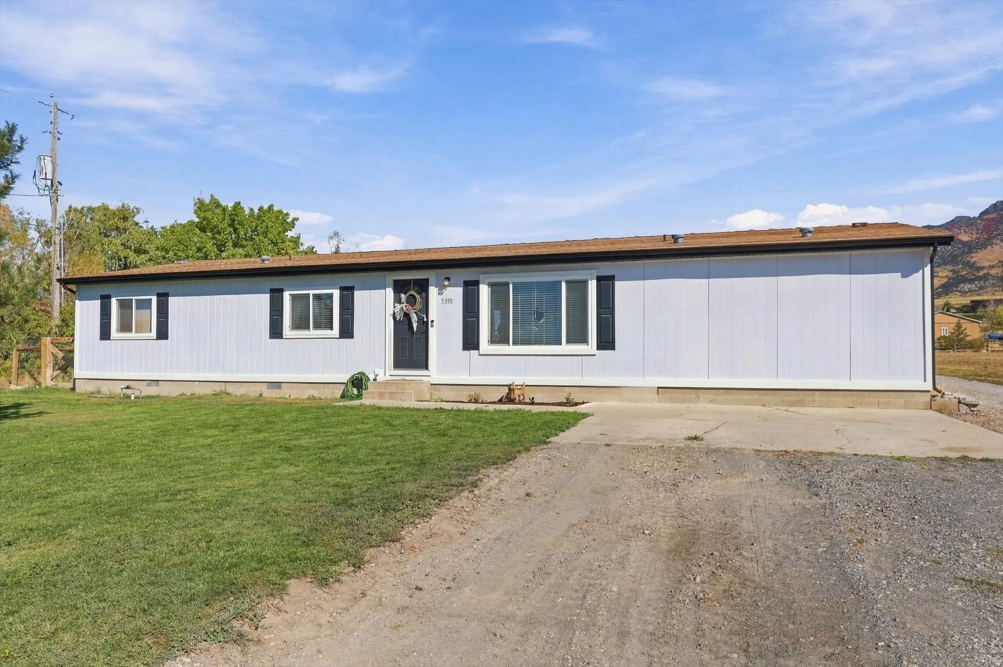Single-story residence featuring light blue siding, a dark brown roof, and multiple windows with dark shutters