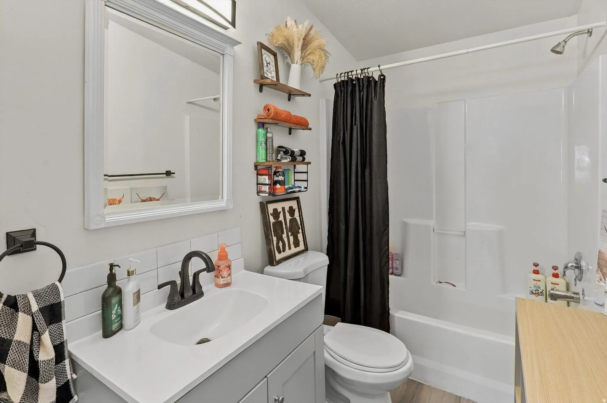 Bathroom featuring a single vanity with storage, white countertop, dark-finish faucet, subway tile backsplash, and a tub/shower combination