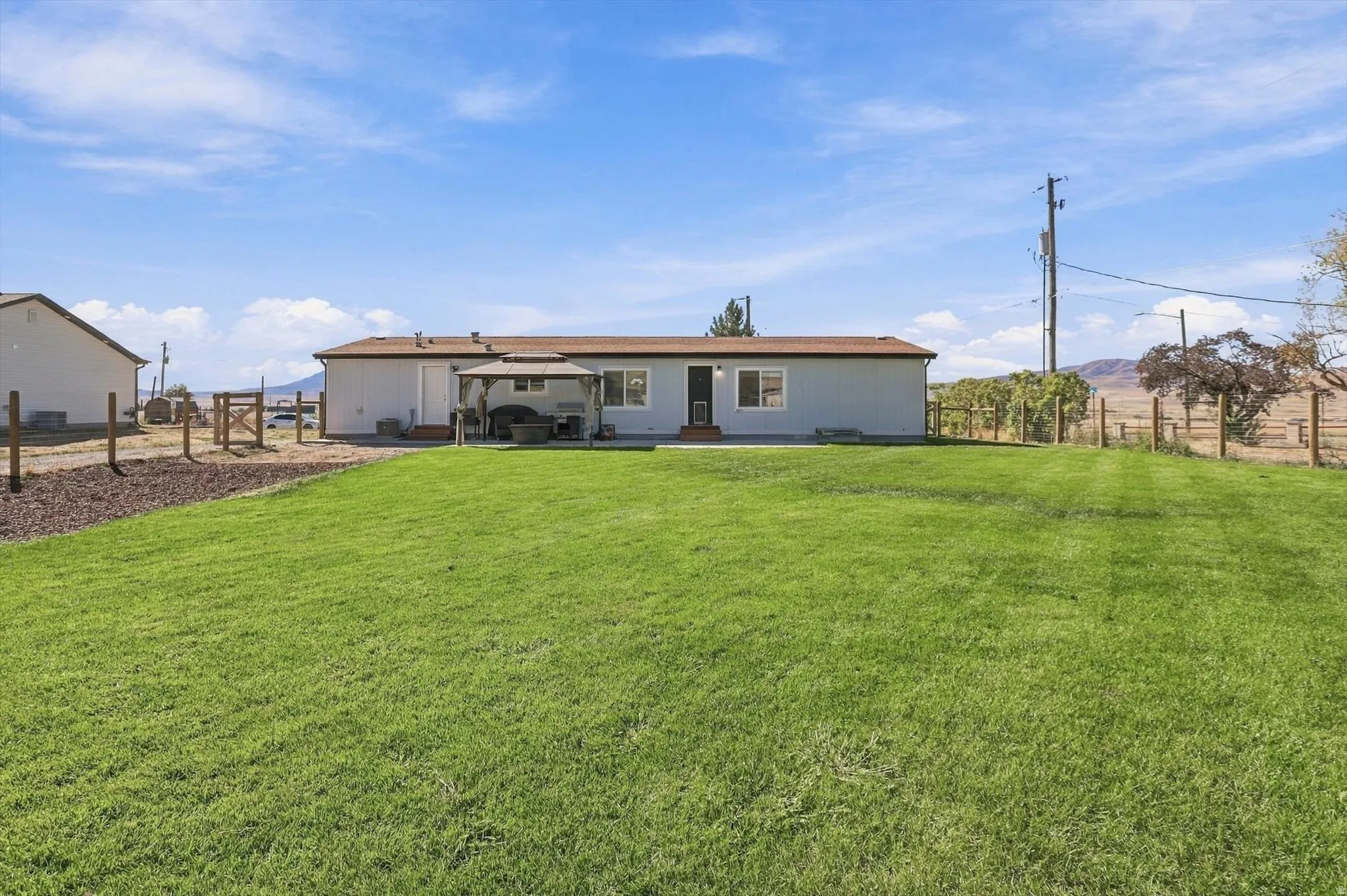 Expansive grass lawn with a light-colored exterior and a brown roof