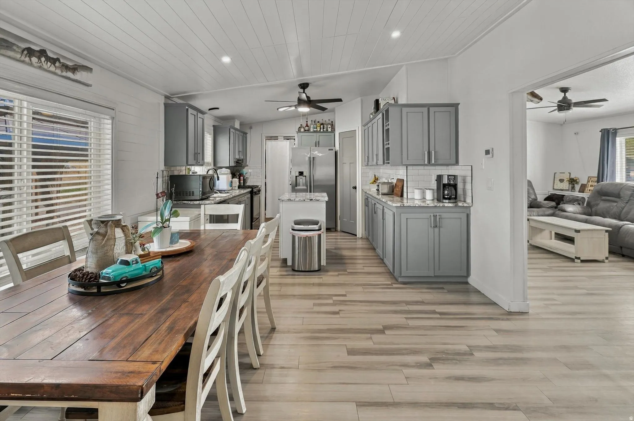 Kitchen featuring grey cabinetry, white subway tile backsplash, stainless steel appliances, and wood-finish flooring