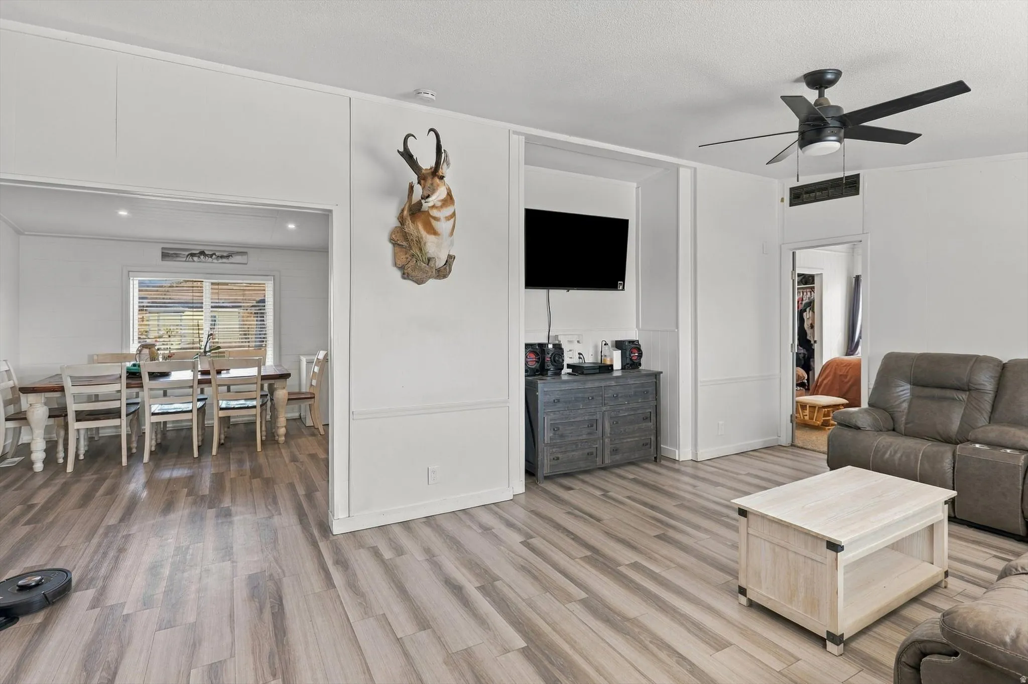 Wood-finish flooring throughout, white wall paneling, recessed lighting, and a ceiling fan with integrated light