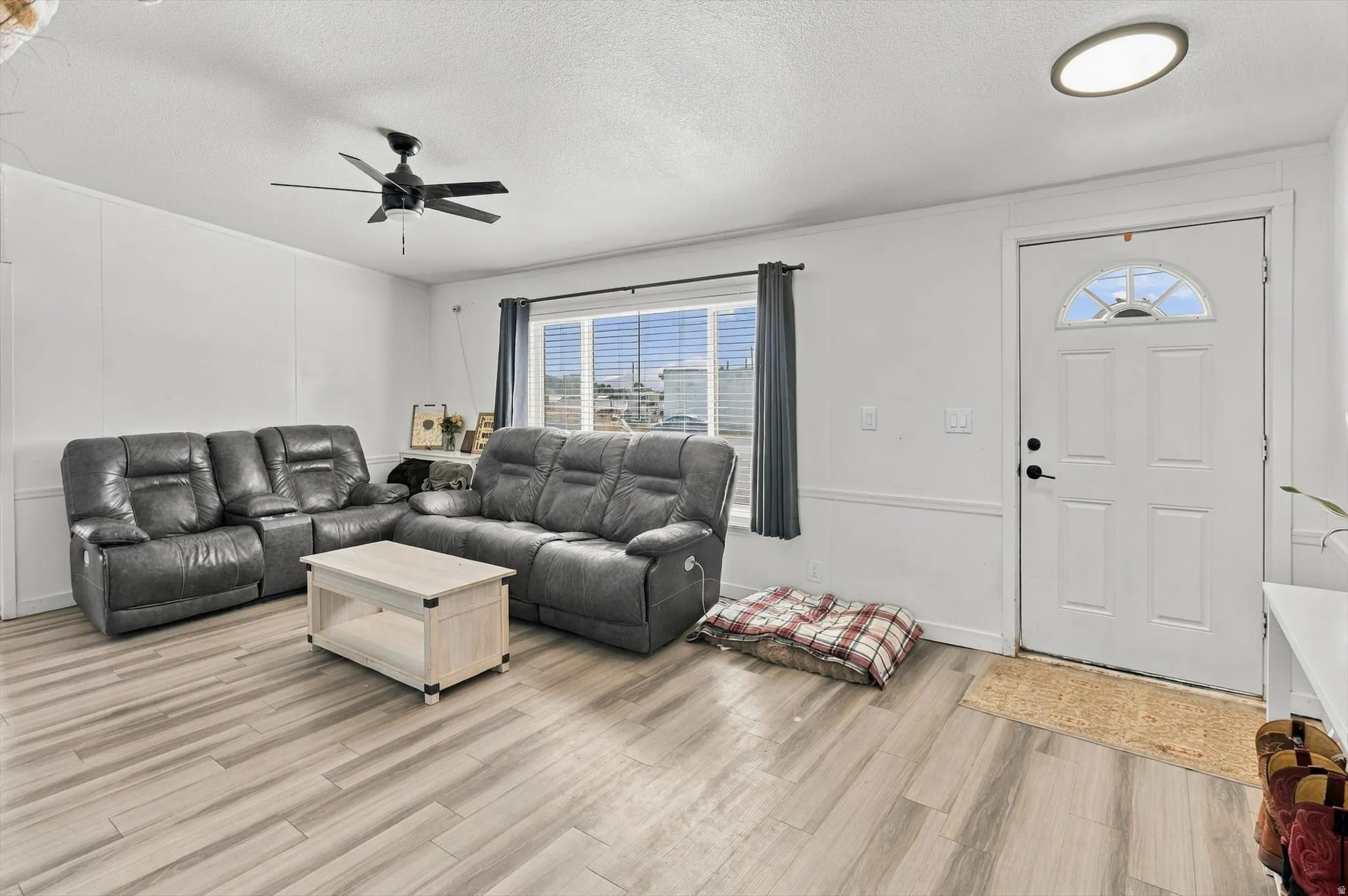 Wood-finish flooring, ceiling fan, white paneled door with arched transom, recessed ceiling light, and window with blinds