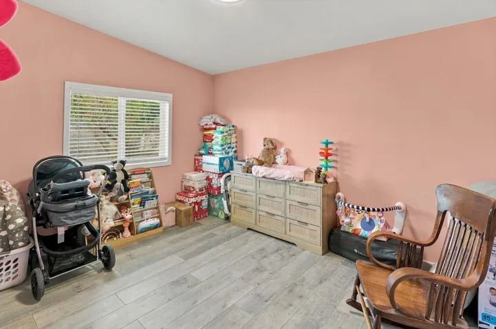 Wood-finish flooring and a single window with horizontal blinds