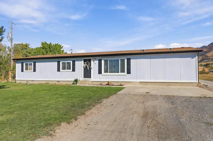 Single-story residence featuring light blue siding, a dark brown roof, and multiple windows with dark shutters