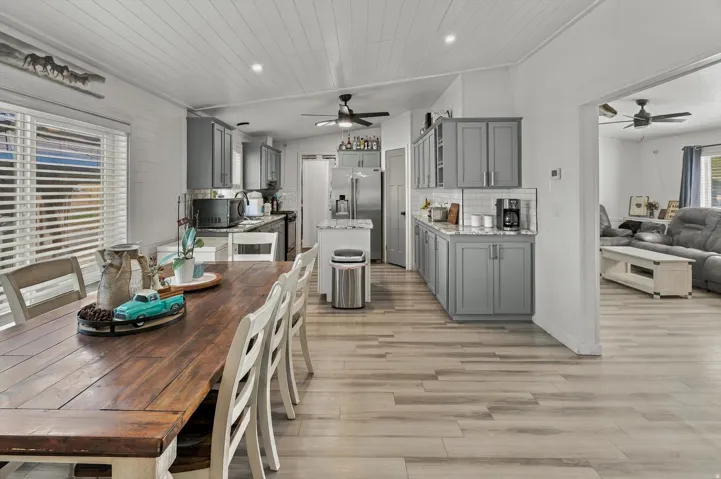 Kitchen featuring grey cabinetry, white subway tile backsplash, stainless steel appliances, and wood-finish flooring