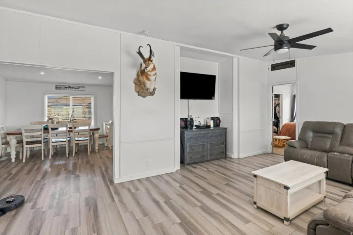 Wood-finish flooring throughout, white wall paneling, recessed lighting, and a ceiling fan with integrated light