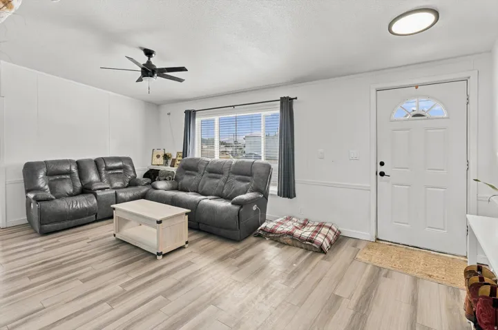 Wood-finish flooring, ceiling fan, white paneled door with arched transom, recessed ceiling light, and window with blinds