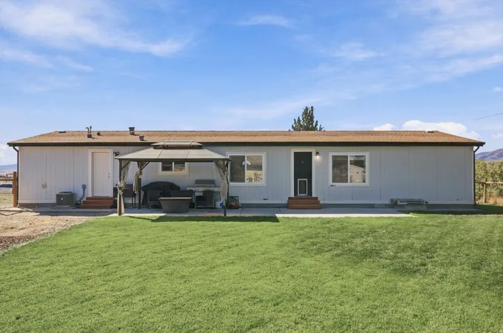 Expansive green lawn, concrete patio, light-toned siding, brown shingle roof, and white-framed windows