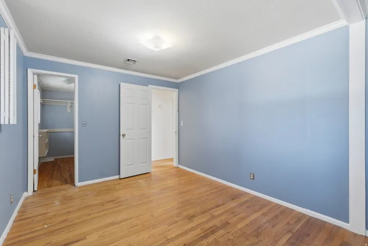 Hardwood flooring, crown molding, white trim, recessed lighting, and a closet with built-in shelving