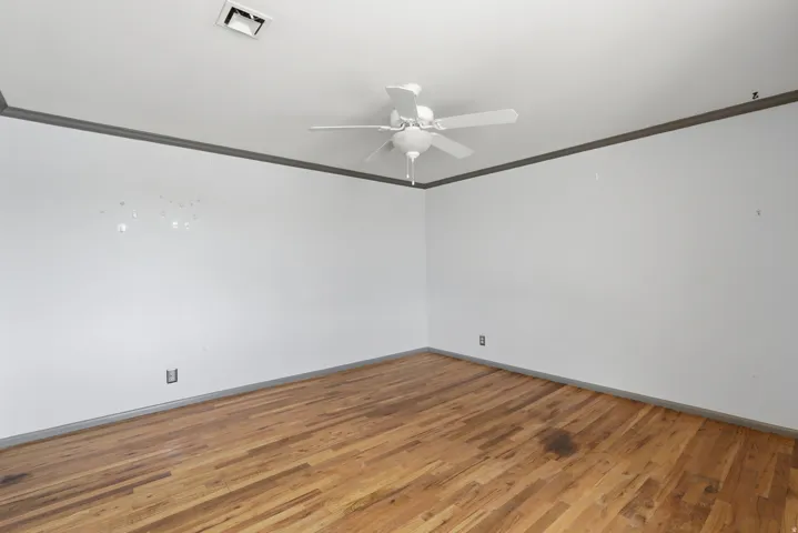 Wood-finish flooring with a ceiling fan and crown molding
