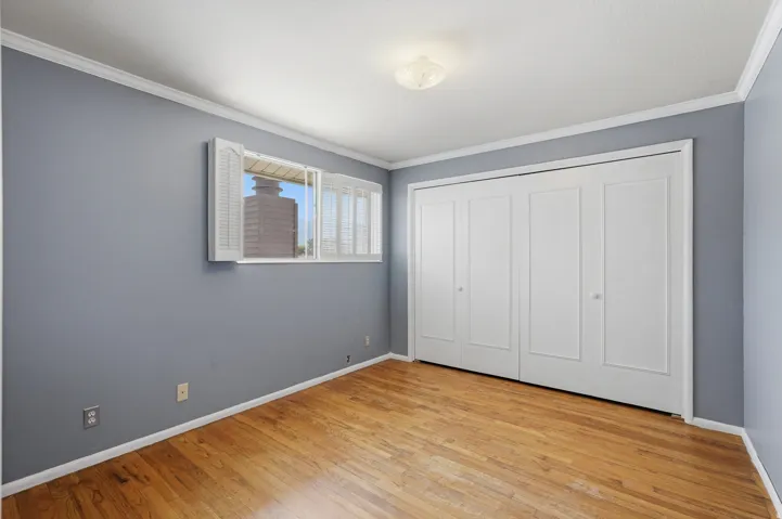 Wide-plank wood flooring, expansive bi-fold closet doors, crown molding, and a flush mount light fixture