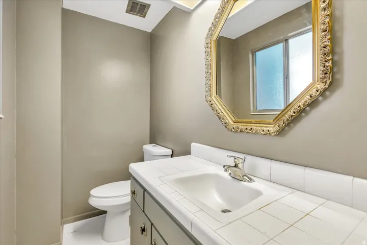 Vanity with white tile countertop, integrated sink, and chrome faucet