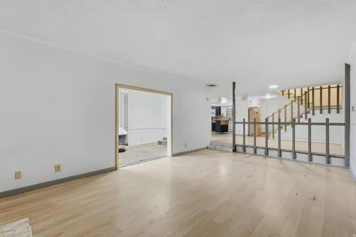 Light wood-finish flooring, white walls, and a staircase with wooden railing