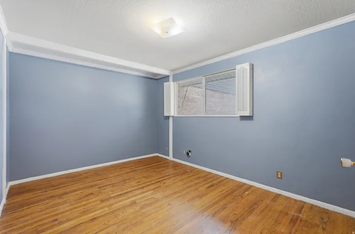 Wood-finish flooring, crown molding, and a flush mount ceiling light