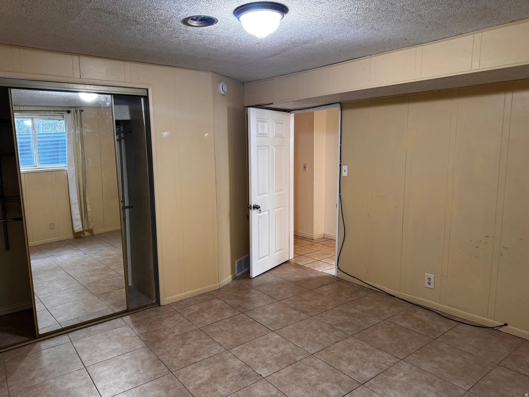 Tile flooring, paneled walls, white interior door, mirrored closet doors, recessed ceiling light