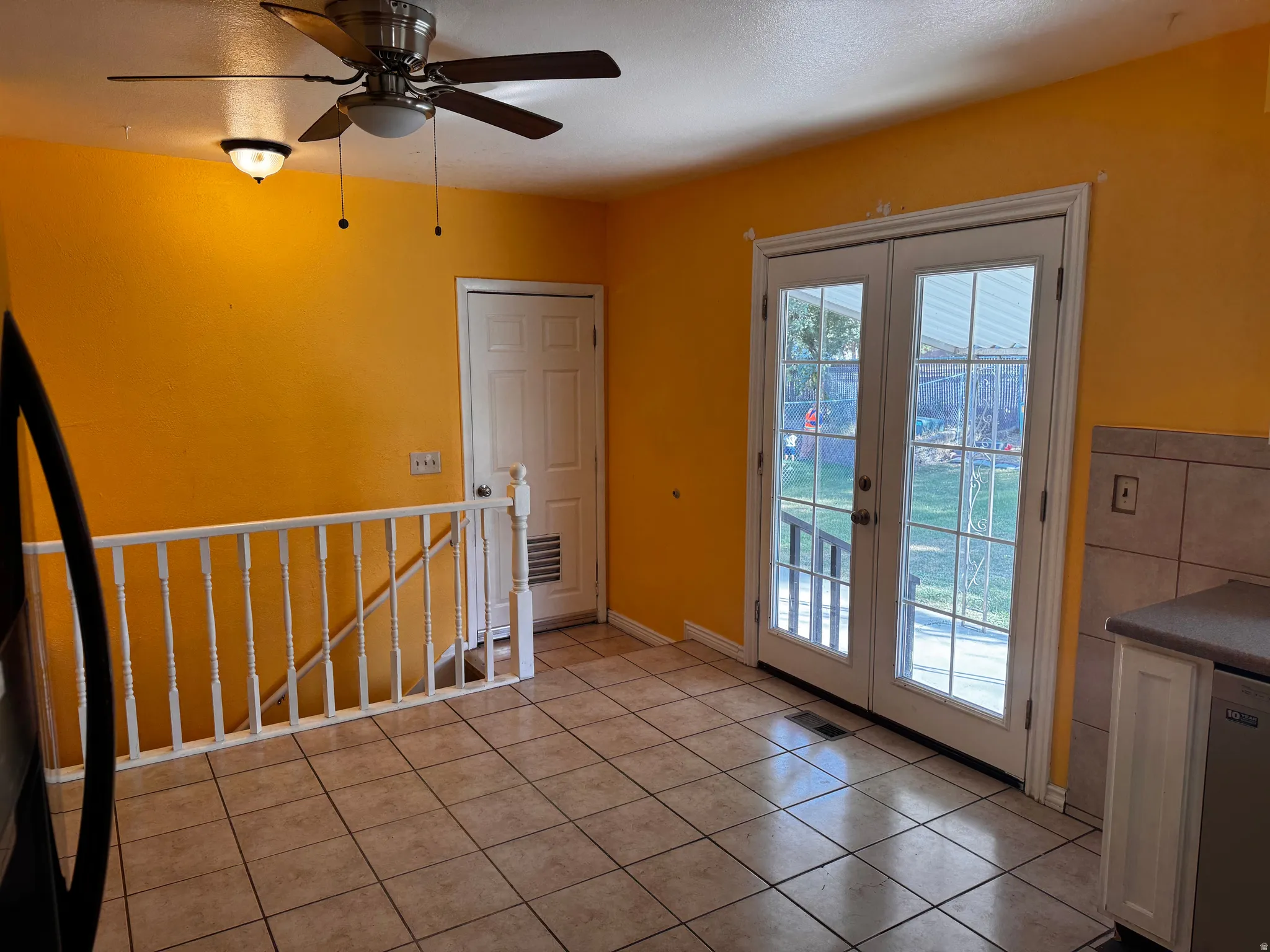 Tile flooring, ceiling fan, recessed lighting, white French doors, and white balustrade