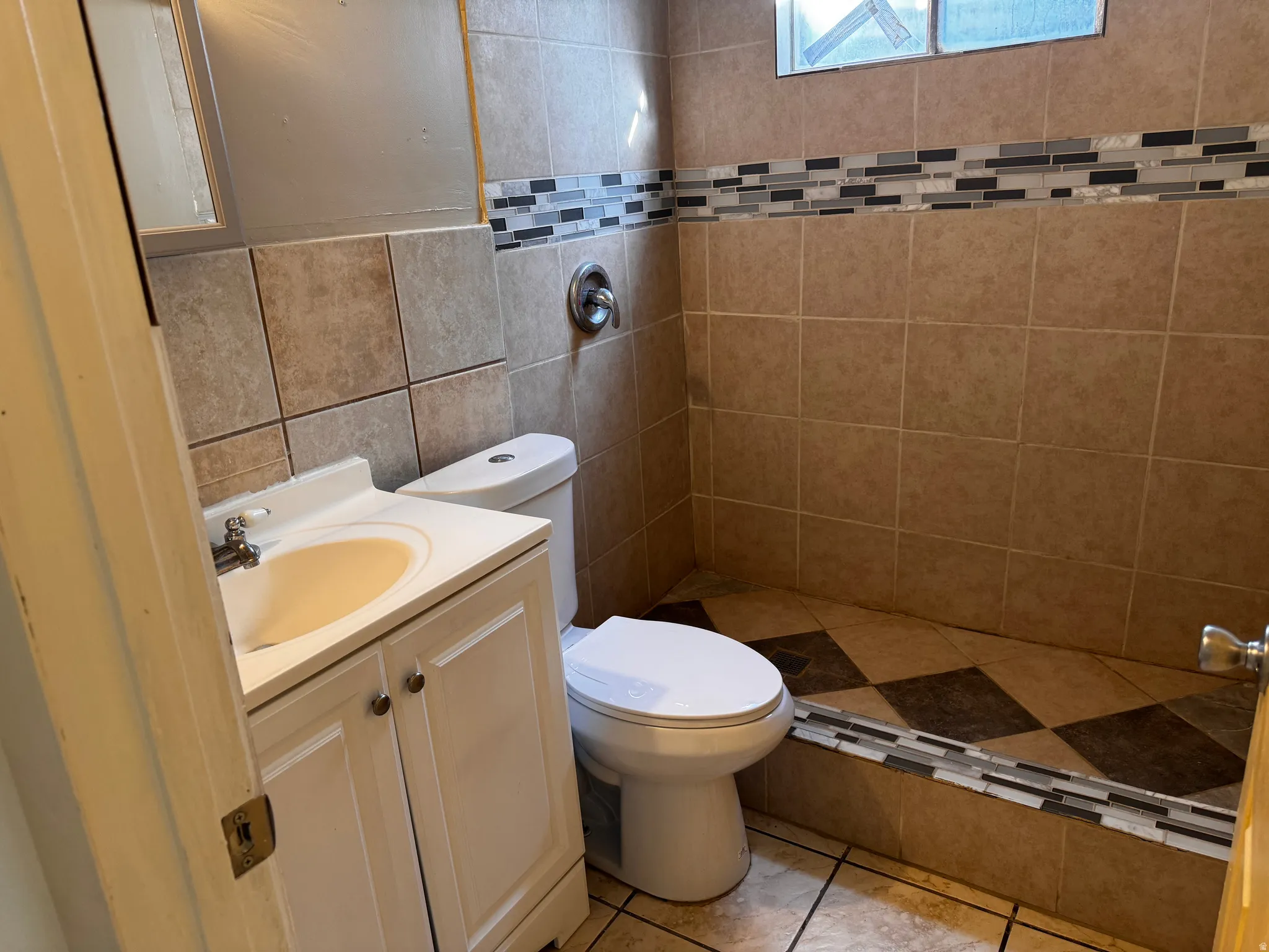 Tile-surround shower with mosaic accent band, checkerboard shower floor, and a single-handle shower fixture
