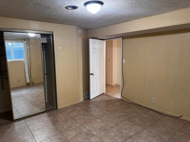 Tile flooring, paneled walls, white interior door, mirrored closet doors, recessed ceiling light