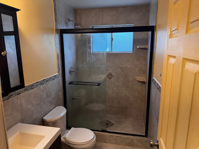 Tile-surrounded shower with glass enclosure, integrated shelving, and window