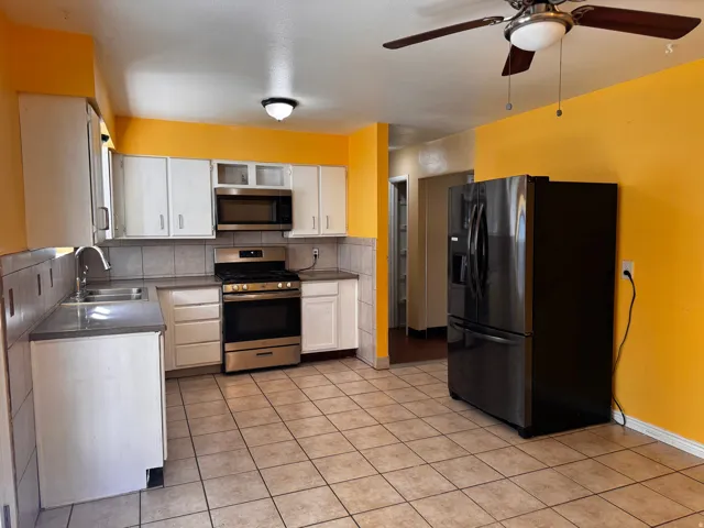 Kitchen featuring tile flooring, white cabinetry, stainless steel appliances, a ceiling fan, and a built-in microwave