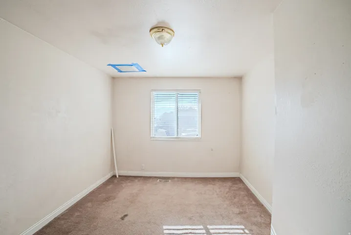 Carpeted room featuring a window with blinds and a ceiling-mounted light fixture