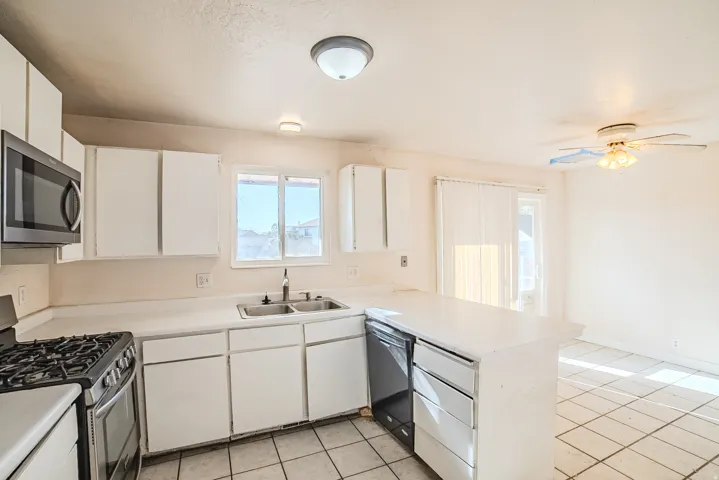 Kitchen featuring white cabinetry, a built-in microwave, a gas range, a dishwasher, and a double basin sink