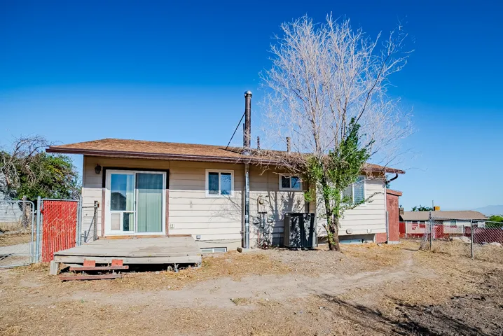 Rear exterior with sliding glass door, an exterior deck, and a fenced perimeter