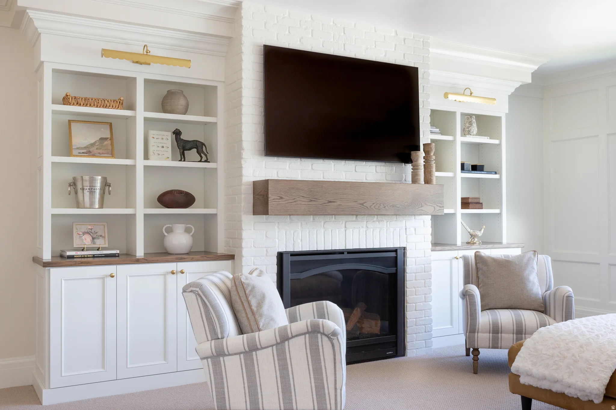 White-painted brick fireplace with a wood-finish mantel, flanked by built-in shelving and lower cabinetry with wood-finish countertops