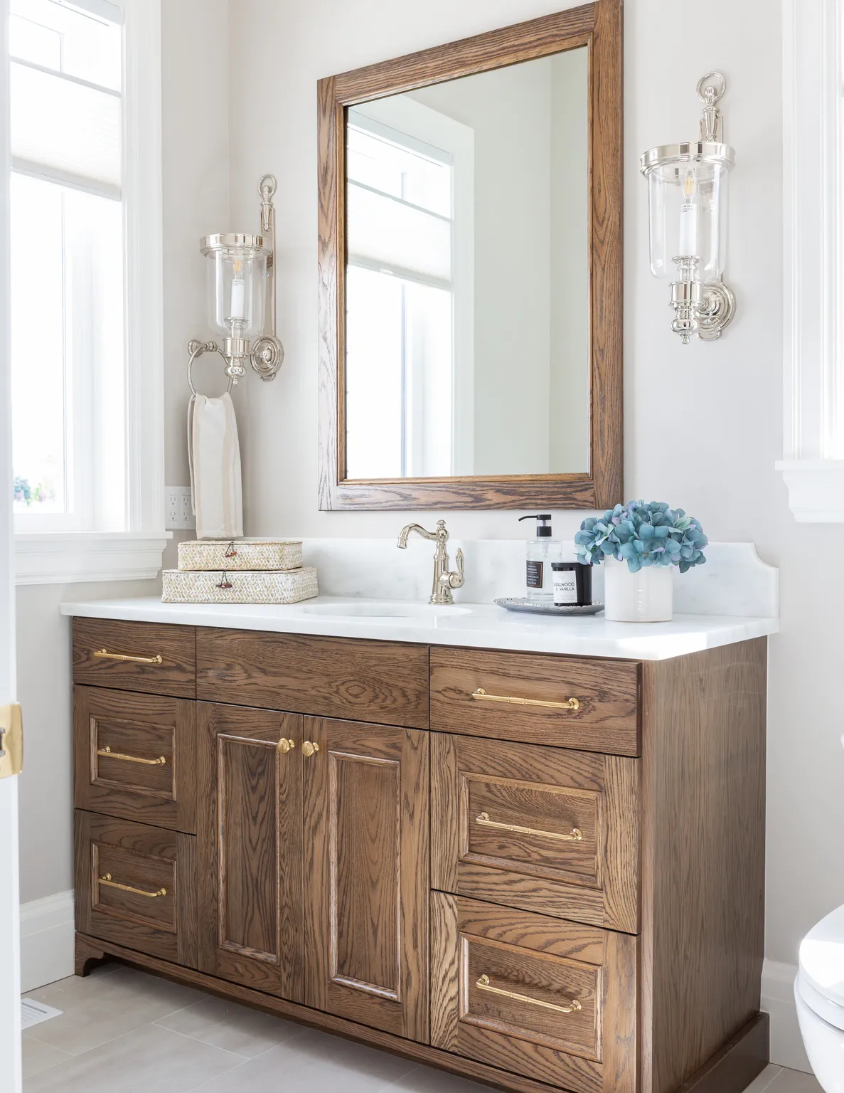 Wood-finish vanity with brass hardware, undermount sink, and stone countertop
