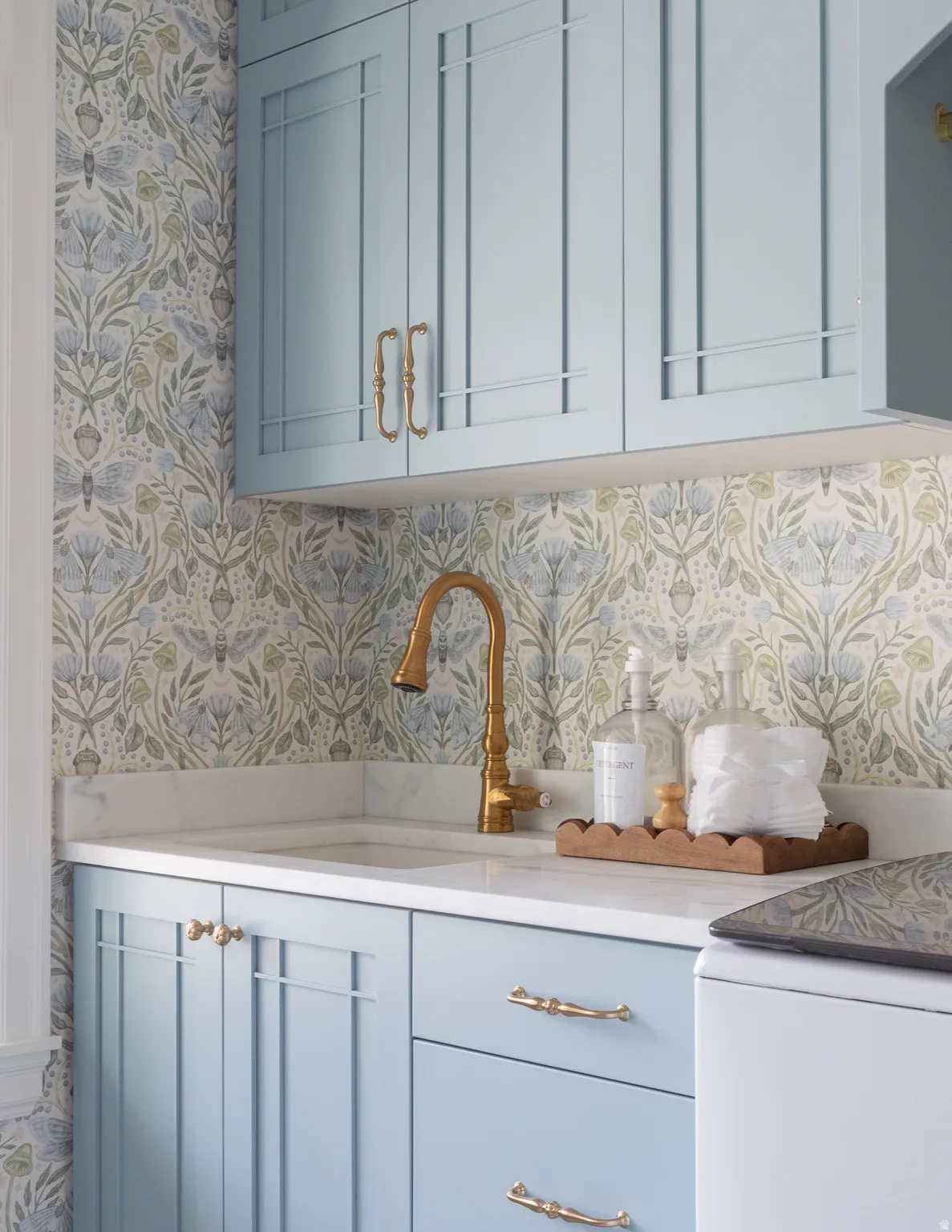 Custom cabinetry with decorative hardware, an integrated sink, polished brass-tone faucet, and stone countertop
