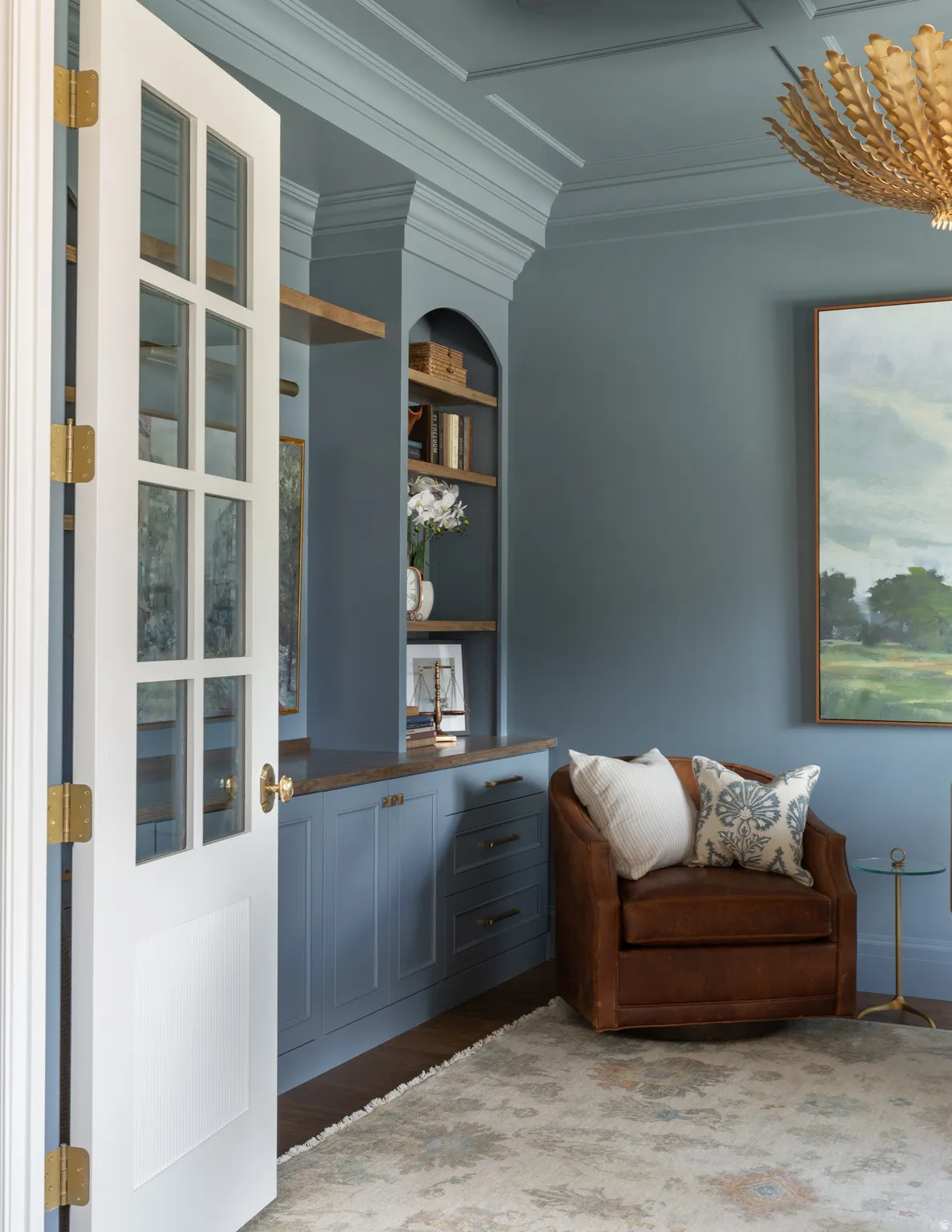 Built-in cabinetry with wood-finish countertop, arched shelving, and paneling