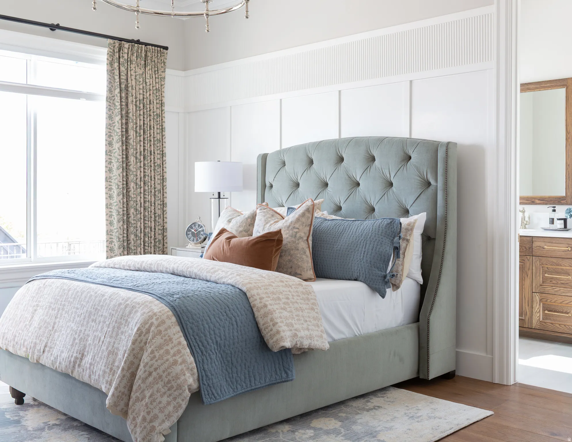 Hardwood flooring, recessed lighting, expansive window, board and batten wall paneling, and an attached bathroom with a wood-finish vanity and framed mirror