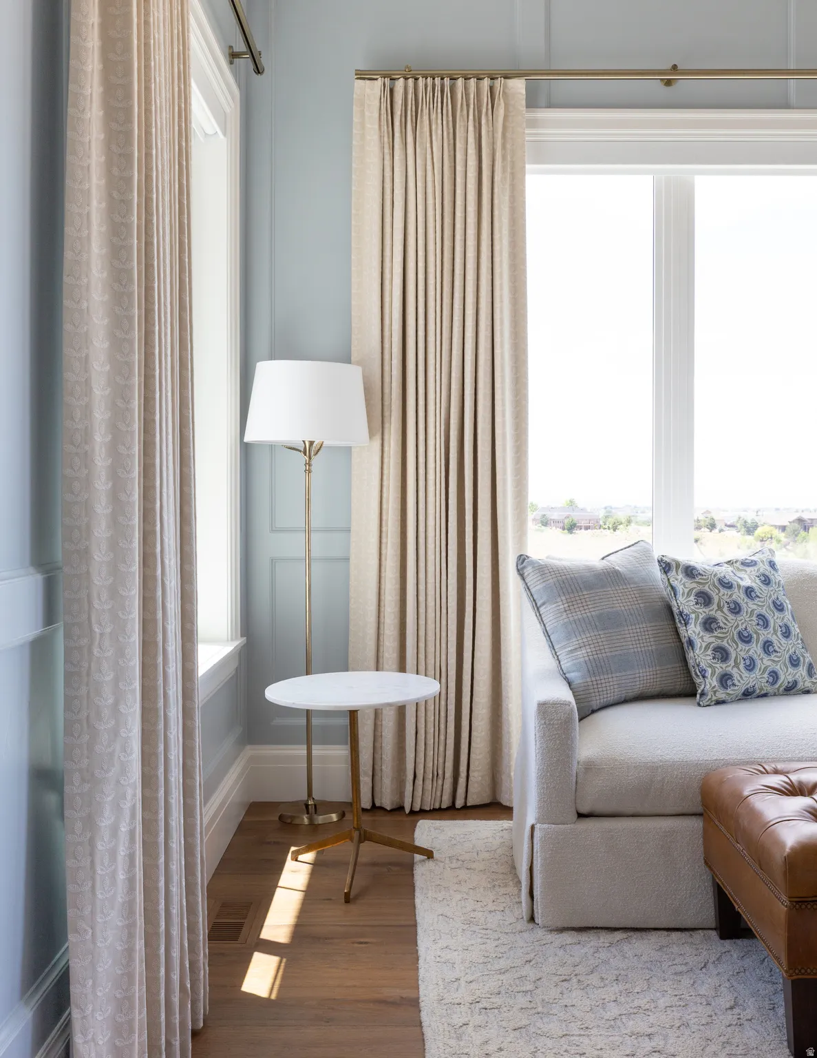 Wood-finish flooring, paneled wall detailing, and a large window with extensive trim