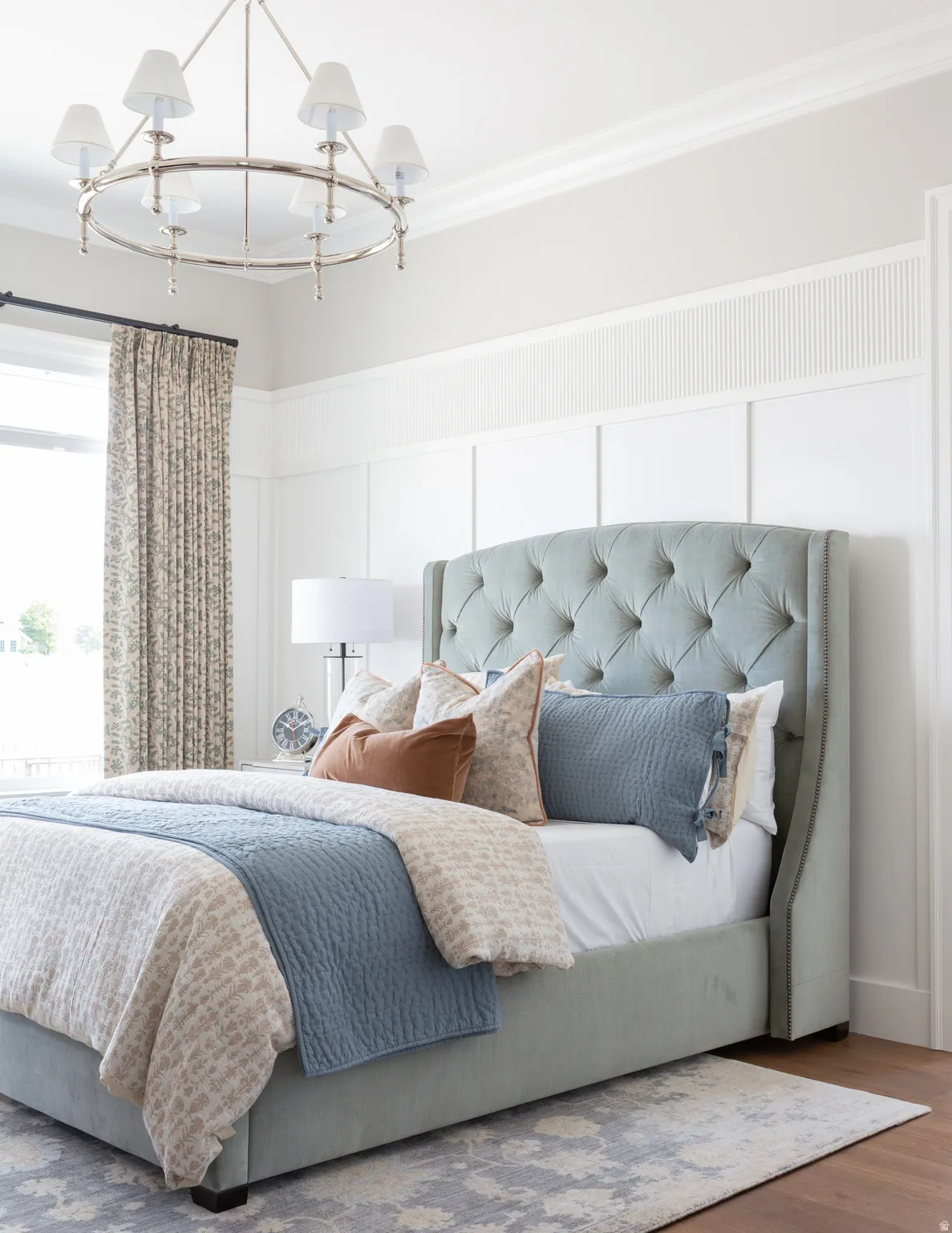 Wood-finish flooring with crown molding, a decorative wall panel accent, and a chandelier with drum shades