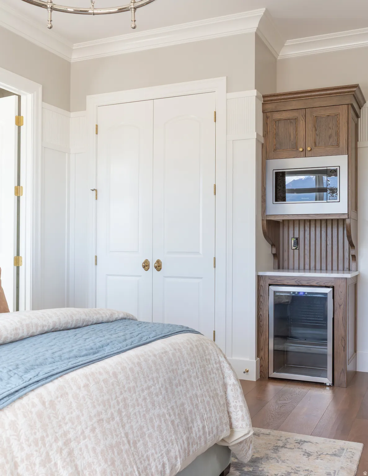 Crown molding, wainscoting, wood-finish flooring, built-in cabinetry with microwave, and beverage refrigerator