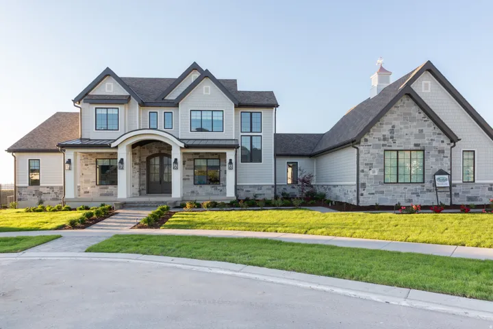 Stone and siding exterior with dark-framed windows, a covered entry, and a cupola accent